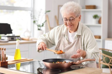 Mutfakta sebze kızartan yaşlı kadın.