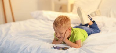 Küçük çocuk yatak odasındaki tablet bilgisayarda çizgi film izliyor.  