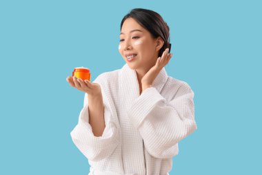 Mavi arka planda yüz kremi olan güzel Asyalı kadın.