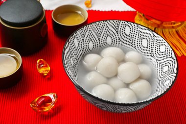 Bir kase tangyuan, çay ve Çin dekoru kırmızı hasırda, yakın plan. Dongzhi Festivali
