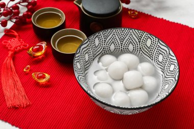 Bir kase tangyuan, çay ve Çin dekoru kırmızı hasırda, yakın plan. Dongzhi Festivali
