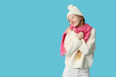 Mavi arka planda sıcak kış giysileri içinde güzel genç bir kadın.