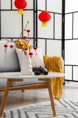 İçinde ağaç dalları olan vazolar, Çin fenerleri ve oturma odasındaki sehpanın üzerine konmuş geleneksel çay seti. Çin Yeni Yıl Kutlaması