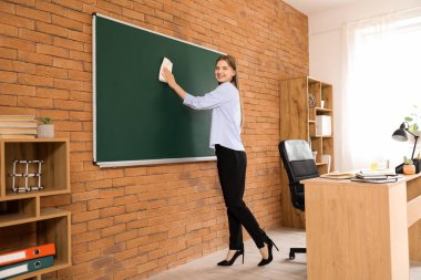 Sınıfta tahtayı silen kadın öğretmen.