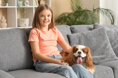 Kral Charles 'ın köpeğiyle oturma odasında kanepede oturan tatlı küçük kız.