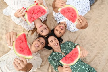 Parkta piknikte karpuz dilimleri olan genç arkadaşlar.