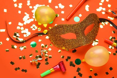 Balonlu karnaval maskesi ve kırmızı arka planda konfeti.