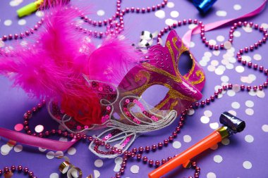 Parti kornası ve eflatun arkaplanlı güzel pembe karnaval maskesi.