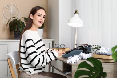 Daktilo ve kitaplarla dolu güzel, mutlu bir kadın yazar. Odadaki masada deftere yazıyor.