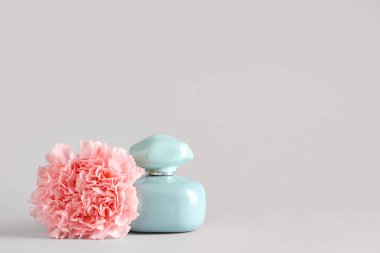 Beyaz arka planda bir şişe parfüm ve karanfil.