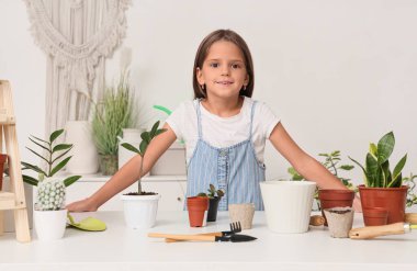 Atölyede bitkileri ve bahçe aletleri olan sevimli küçük bir kız.