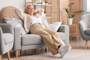 Yaşlı kadın evdeki kanepede dinleniyor.