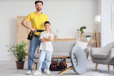 Baba ve küçük oğlu evde iskemle topluyor.