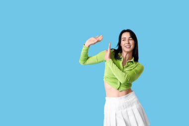 Mavi arka planda dans eden mutlu genç kadın