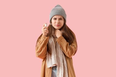 Pembe arka planda astım spreyi olan hasta genç bir kadın.