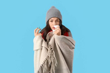 Mavi arka planda burnu akan hasta genç bir kadın.