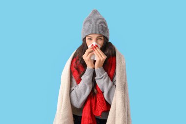 Mavi arka planda burnu akan hasta genç bir kadın.