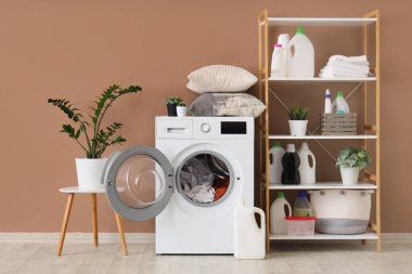 Çamaşır makinesi, raf ünitesi ve deterjanı olan bir çamaşırhane.