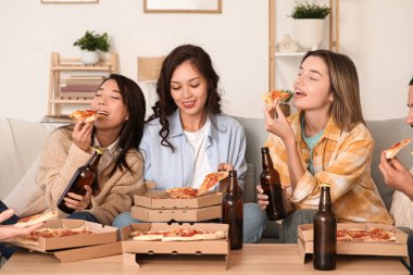 Ev partisinde kanepede pizza yiyen kız arkadaşlar.