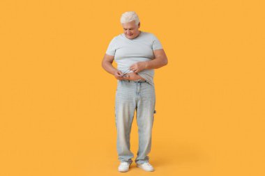 Sarı arka planda tükenmez kalem kullanan şeker hastası olgun bir adam.