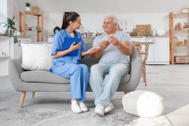 Glukometresi olan şeker hastası olgun bir adam ve evdeki kanepede oturan bir doktor.