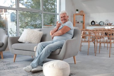 Şeker hastası, olgun bir adam evdeki kanepede tükenmez kalem kullanıyor.