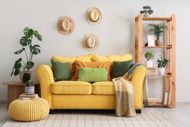 Sarı kanepe ve kitap ve kaktüsle birlikte oturma odasının içinde.