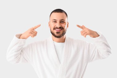 Gülümseyen genç adam beyaz arka planda yüzündeki göz bantlarını gösteriyor.