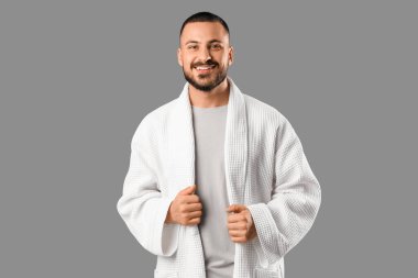 Gri arka planda gülümseyen genç adam