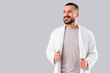 Gri arka planda, bornozlu genç yakışıklı adam.