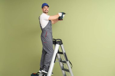 Erkek teknisyen yeşil duvarı deliyor.