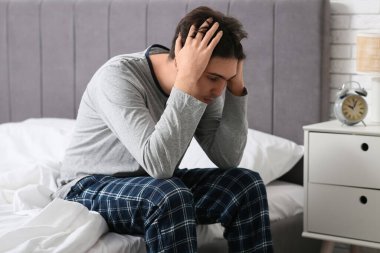 Depresyondaki genç adam yatak odasında oturuyor.