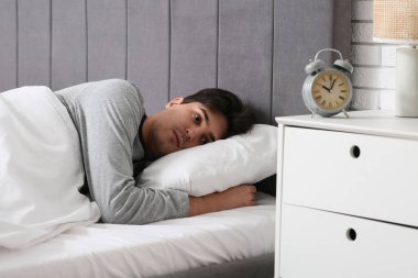 Depresyondaki genç adam yatak odasında yatıyor.