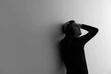 Aydınlık duvarın yanındaki depresif genç adamın siyah beyaz portresi