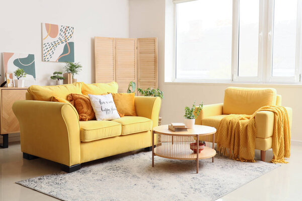 Yellow sofa, armchair and coffee table in interior of living room