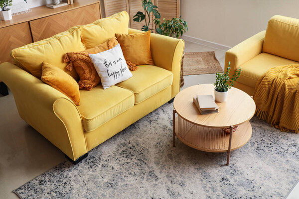 Yellow sofa, armchair and coffee table in interior of living room