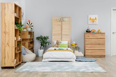 Yatak, raf üniteleri ve çekmeceleri olan çocuk odasının içinde.