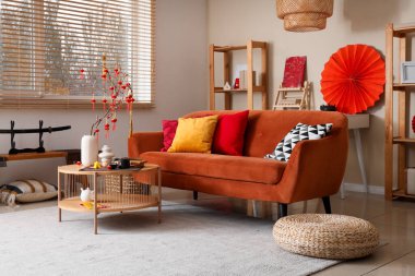 Çin Yeni Yılı için dekore edilmiş oturma odasının içinde kırmızı kanepe ve çay seti var.