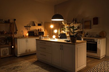 Geceleri tezgahları, rafları ve parlayan lambaları olan karanlık bir mutfak.