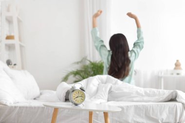 Yatak odasında uzanan kadına karşı alarmlı saat, yakın plan.