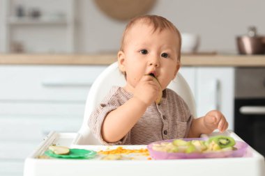 Evde armut yiyen şirin bir bebek.