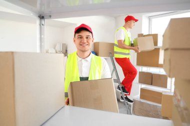 Erkek yükleyici depodaki rafa bir kutu koyuyor.