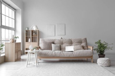 Oturma odasının içi boş dizüstü bilgisayarlı kanepe, masa ve bitkilerle dolu.