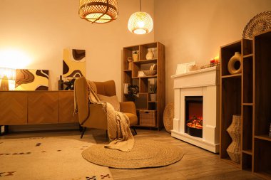 Geceleri şömineli, koltuklu ve parlayan lambalı oturma odasının içinde.