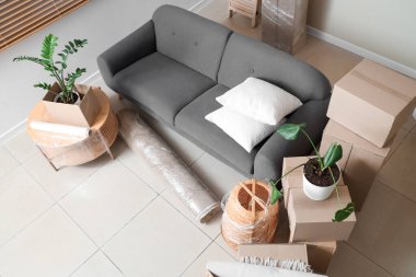 Hareket gününde siyah kanepe, masa ve karton kutularla dolu bir oda.