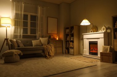 Geceleri şöminesi, kanepesi ve parlayan lambası olan karanlık oturma odasının içinde.