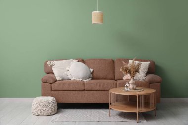 Konforlu kanepe ve yeşil duvarın yanındaki masa