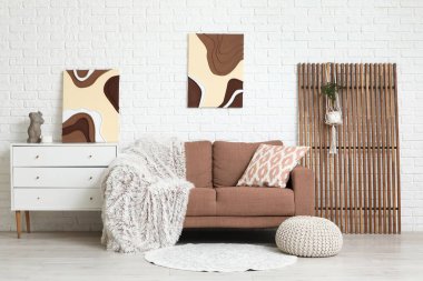 Oturma odasının içinde yastıklı, ekoseli ve resimli rahat bir kanepe.