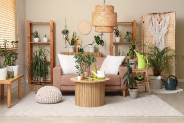 Oturma odasının içinde kanepe, yeşil bitkiler ve bahçe malzemeleri var.