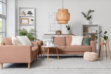 Oturma odasının içinde kanepeler, raf üniteleri ve bitkiler var.